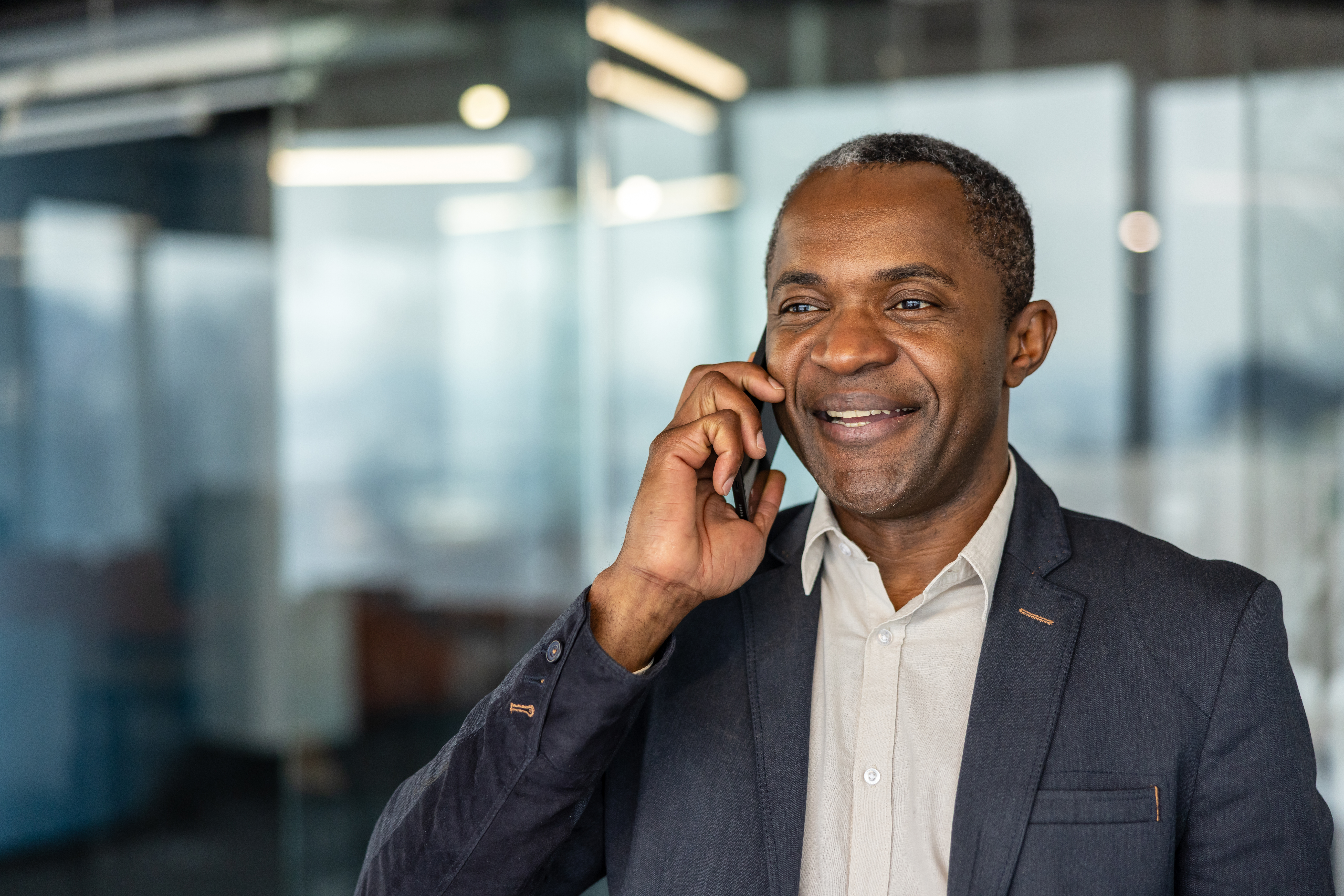 Confident mature professional man communicating cheerfully on a mobile phone, representing success, connection, and technology in a corporate environment